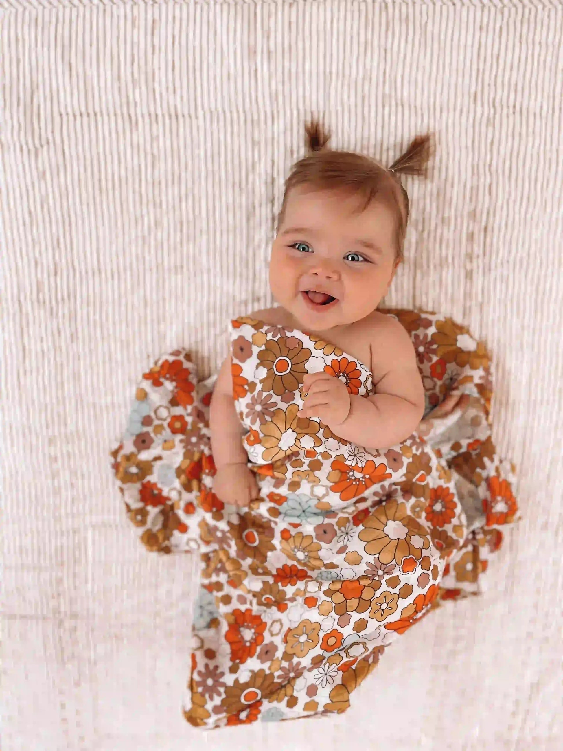 Baby girl smiling in Bloom muslin swaddle wrap